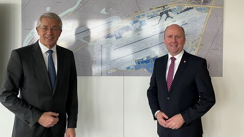 Dr. Stefan Schulte und Europastaatssekretär Uwe Becker stehen nebeneinander vor einer Karte und lächeln in die Kamera