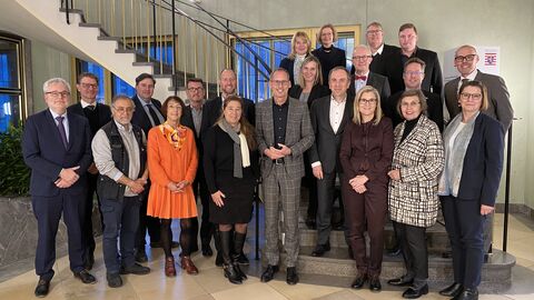 Teilnehmerinnen und Teilnehmer des Neuen Bündnis Fachkräftesicherung Hessen stehen gemeinsam vor einer Treppe zum Gruppenbild aufgestellt.