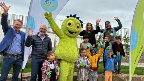 Beteiligte am Sauberhaften Kindertag gemeinsam mit Maskottchen "Müllmo" und Kindern.