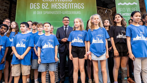 Eine Gruppe Kinder steht mit Ministerpräsident Boris Rhein auf einer Bühne