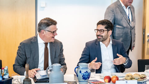 Ministerpräsident Boris Rhein und Wirtschaftsminister Mansoori auf der Kabinettssitzung Zwei Männer sitzen nebeneinander an einem Tisch und reden miteinander.