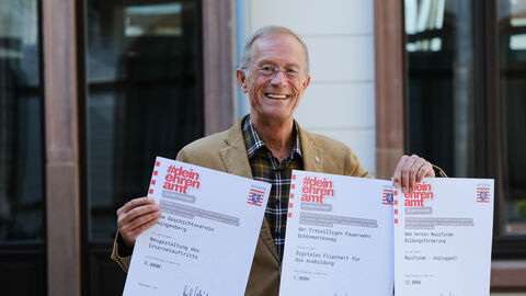 Staatsminister Axel Wintermeyer hält drei Förderzusagen in der Hand