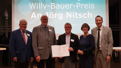 Fünf Personen stehen vor einer Leinwand auf der "Verleihung Willy-Bauer-Preis an Jörg Nitsch" steht